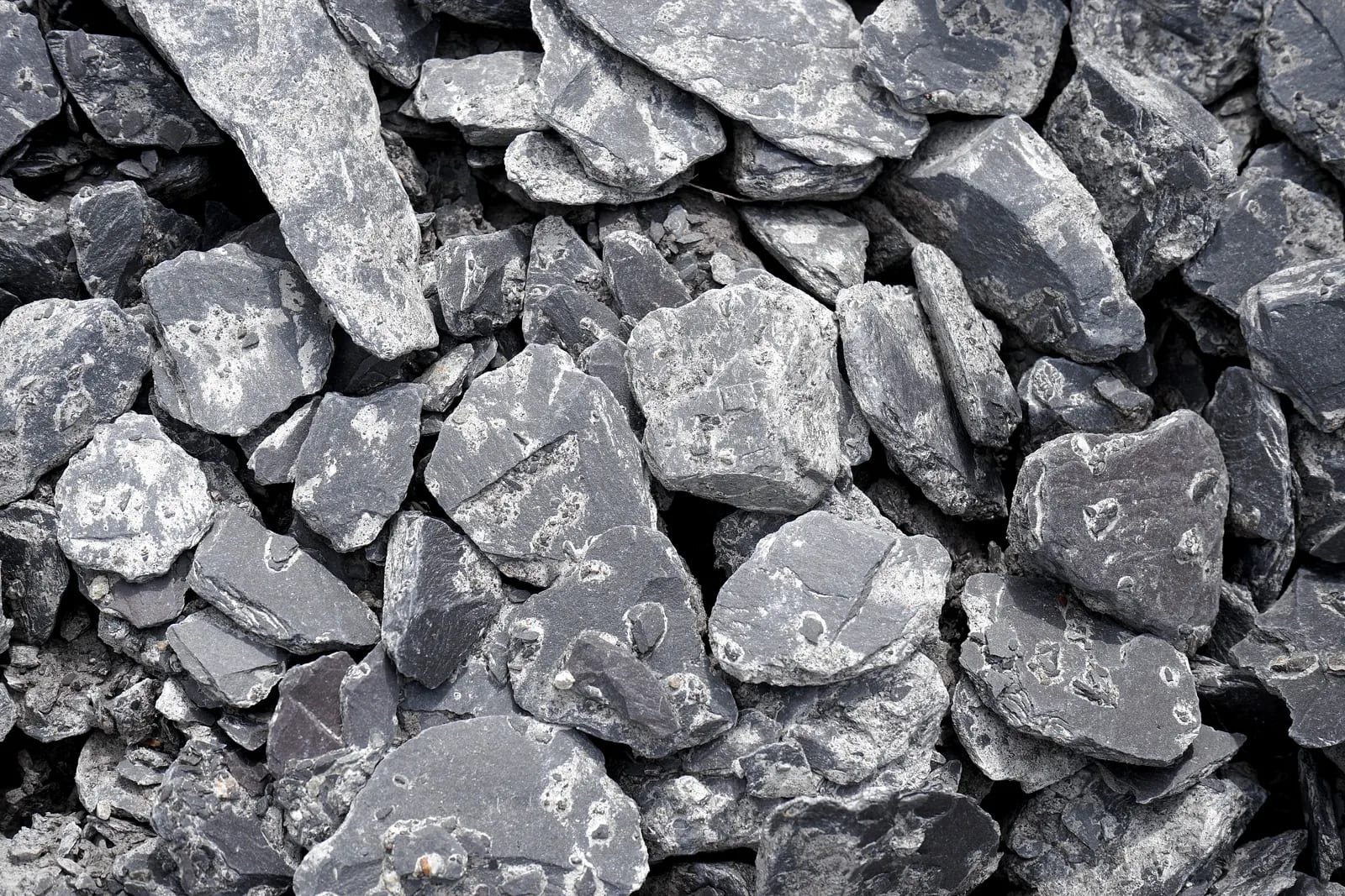Montón de fragmentos de pizarra gris con superficies rugosas y aristas irregulares, vistos de cerca