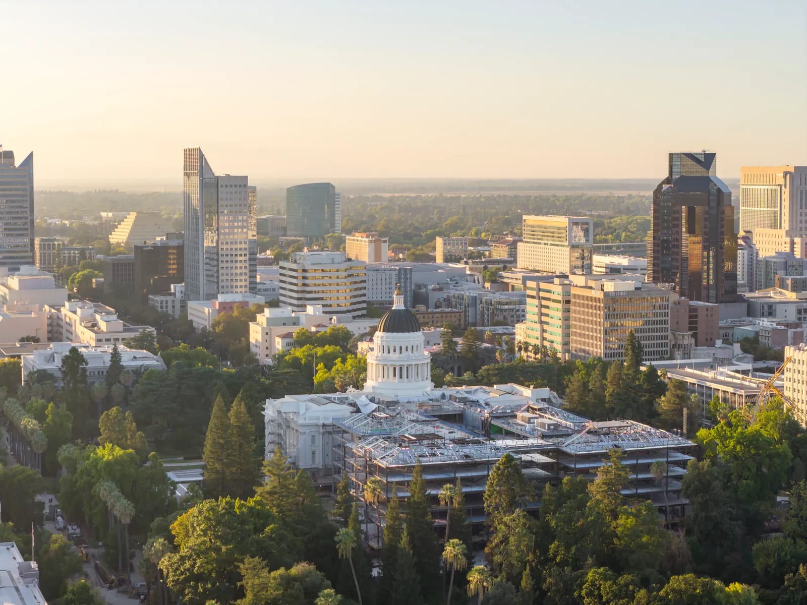 Vista aérea del centro de Sacramento al atardecer, con el Capitolio del estado de California entre edificios y arbolado