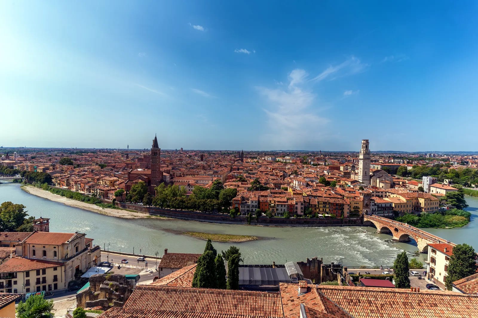 Vista aérea de Verona con el río Adige serpenteando entre tejados y torres históricas bajo un cielo despejado