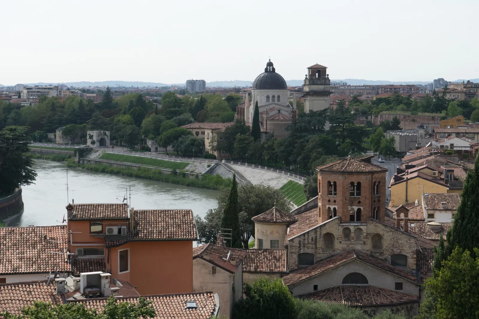 Vista panorámica de Verona con el río Adige, la cúpula de San Giorgio in Braida y el campanario de ladrillo de Santo Stefano entre tejados y arboleda