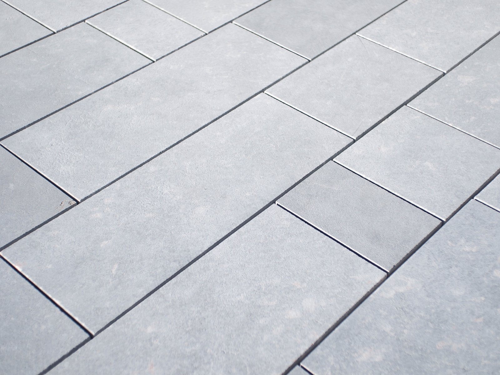 Pavimento de losas rectangulares de mármol gris con acabado arenado, colocadas en espiga
