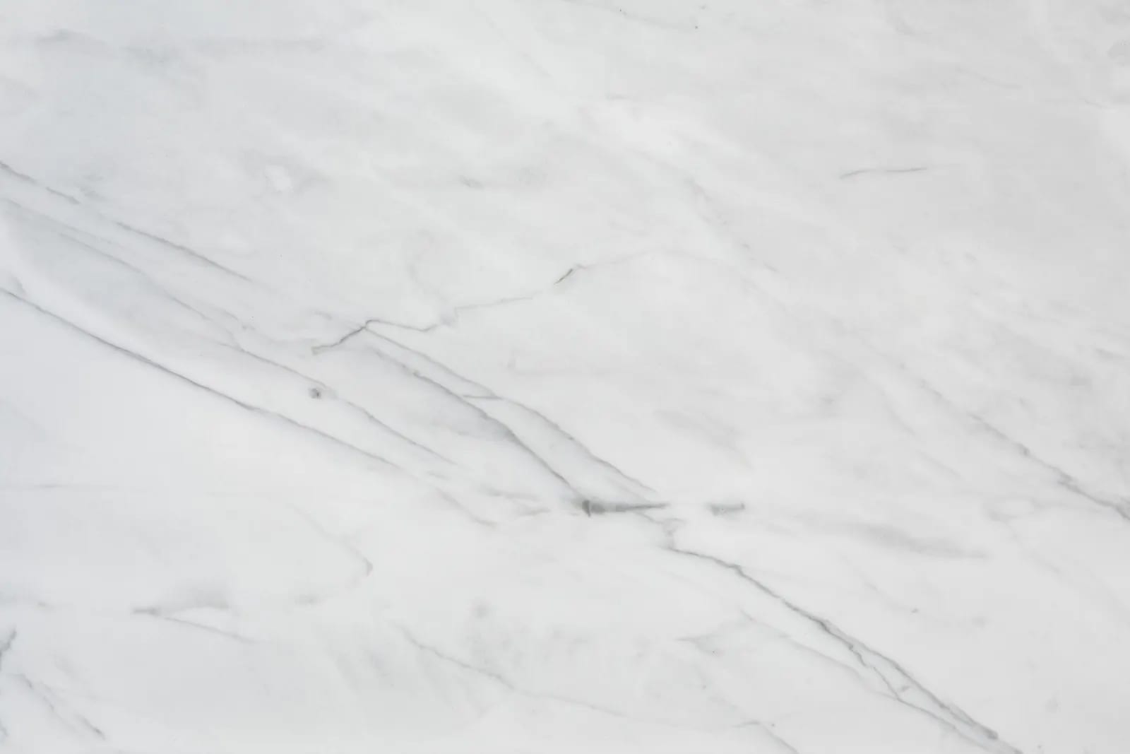 Superficie de mármol blanco con vetas grises finas que la cruzan en diagonal, vista de cerca y con luz uniforme
