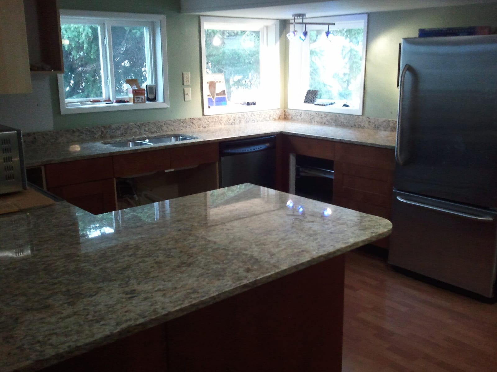 Cocina en obra con encimeras de granito pulido de grano beige y gris alrededor del fregadero y una península